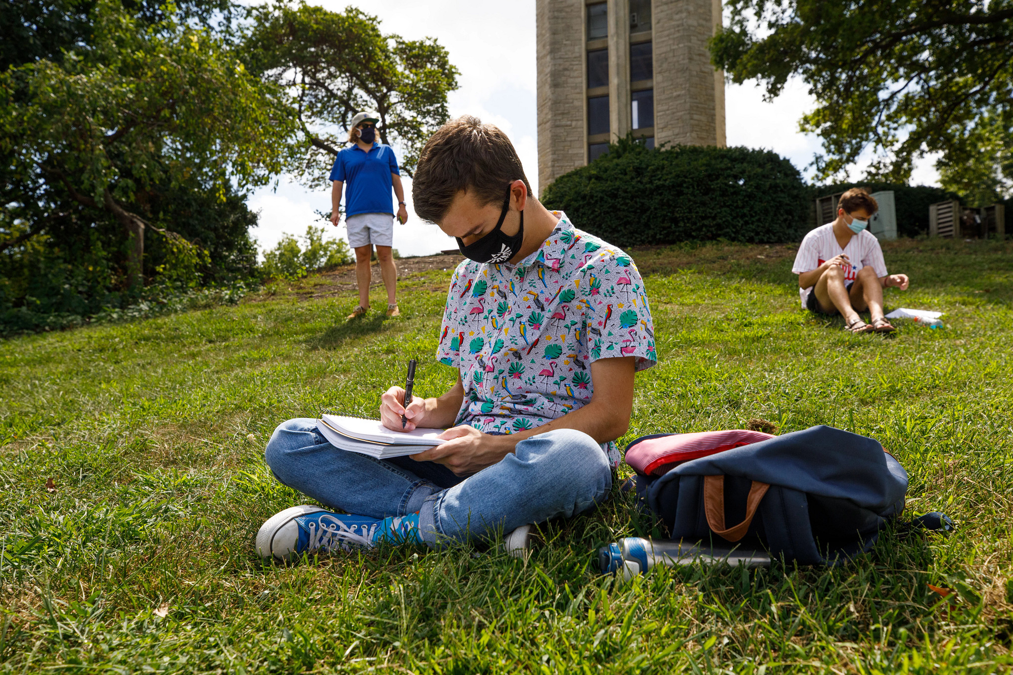 Student studies on lawn in front of bell tower