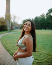 Young woman doind an over the shoulder smile in a half top on campus